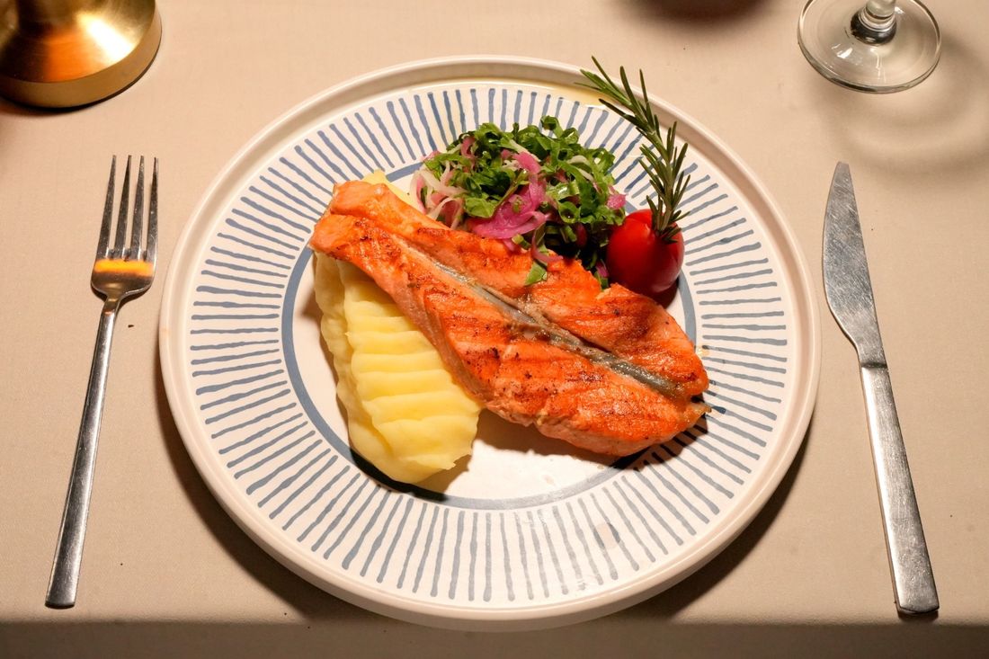 Grilled salmon plated with mashed potatoes and marinated greens
